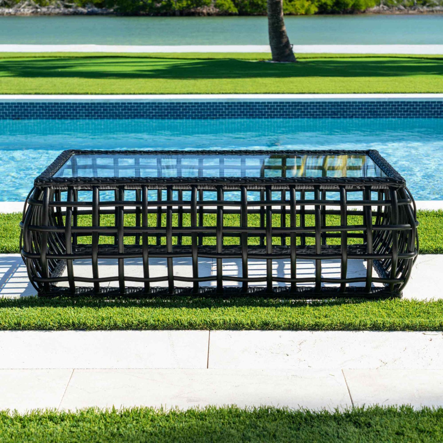 Black synthetic wicker outdoor rectangular coffee table with a tempered glass top