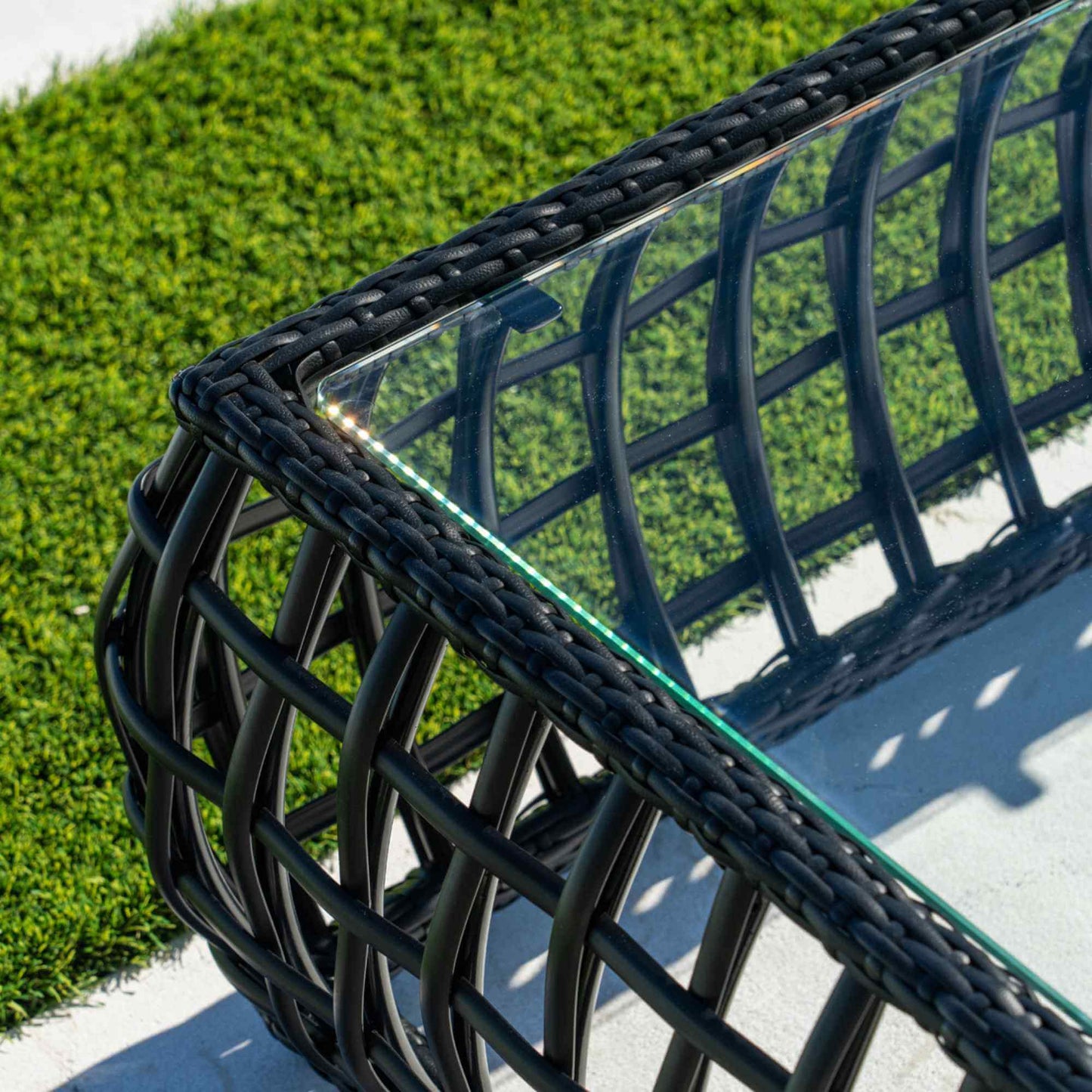 Black synthetic wicker outdoor rectangular coffee table with a tempered glass top