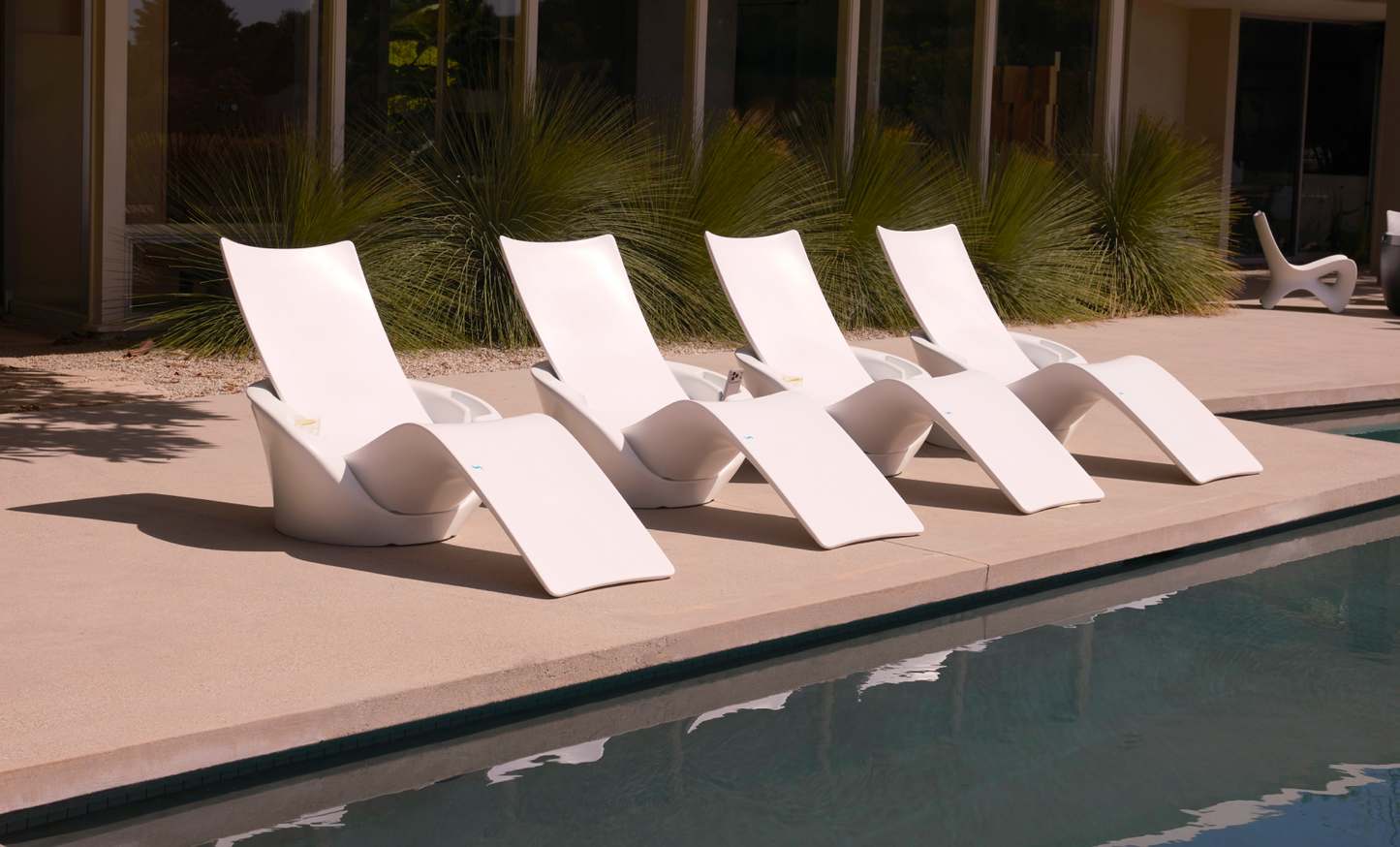 Four white Autograph Chaise Armrest Consoles lined up poolside