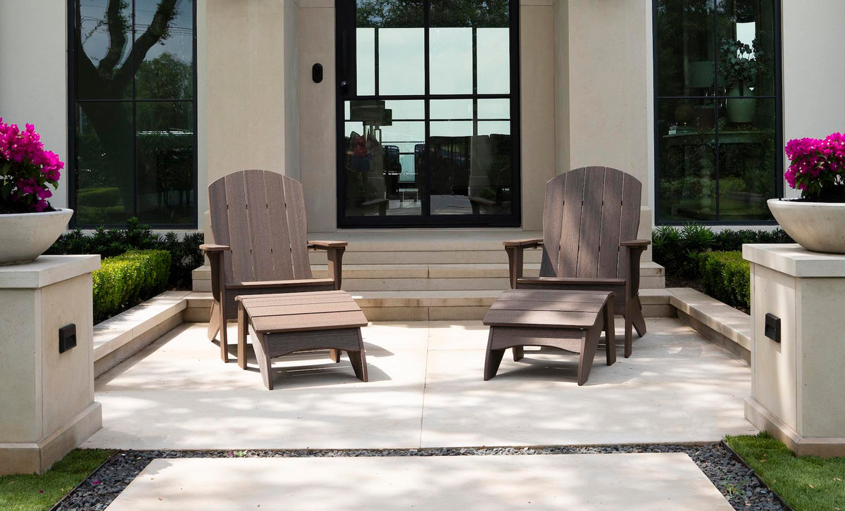 Two Legacy Adirondack chairs with footrests on a modern patio