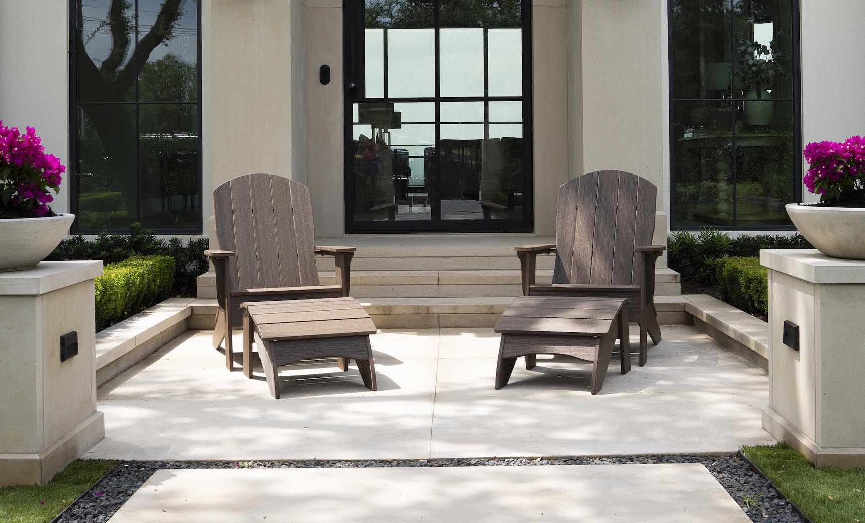 Two Legacy Adirondack chairs with footrests on a modern patio