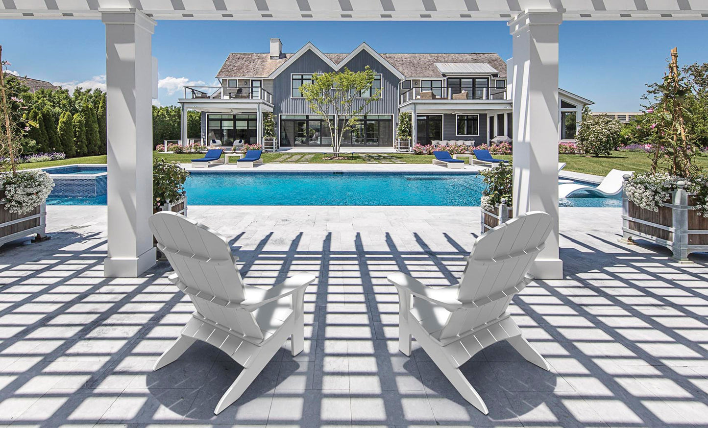White Legacy Adirondack chairs under a pergola beside a pool