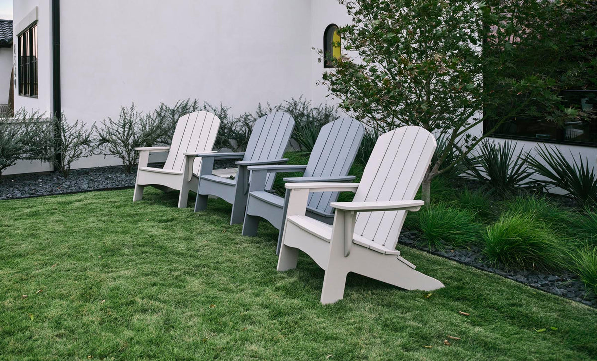 Four Legacy Adirondack chairs in light and dark gray on a lawn