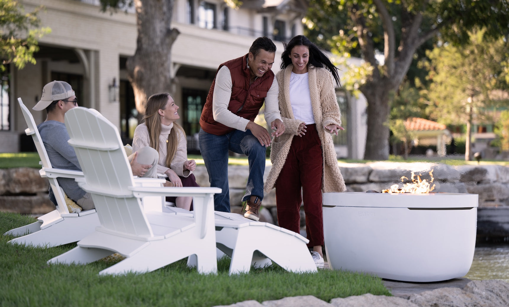 People resting their feet on white Legacy Adirondack Ottomans by a fire pit