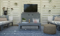 Outdoor patio area with gray furniture, TV, and decorative elements.