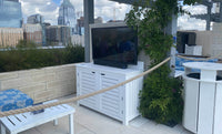 Outdoor patio with a TV on a white cabinet, city skyline in the background