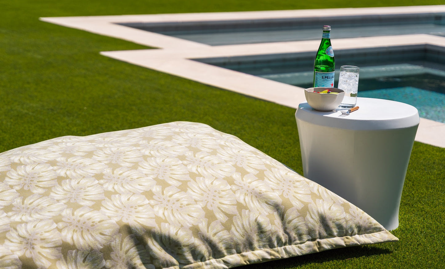 Affinity Side Table holding sparkling water, a glass, and sliced fruit by a pool