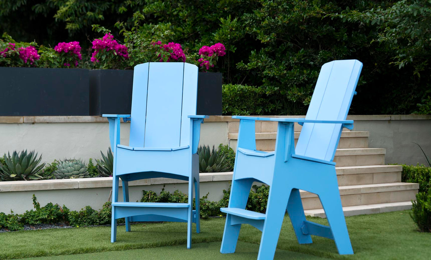 Tall Mainstay Adirondack chairs on a lawn with flowering steps behind