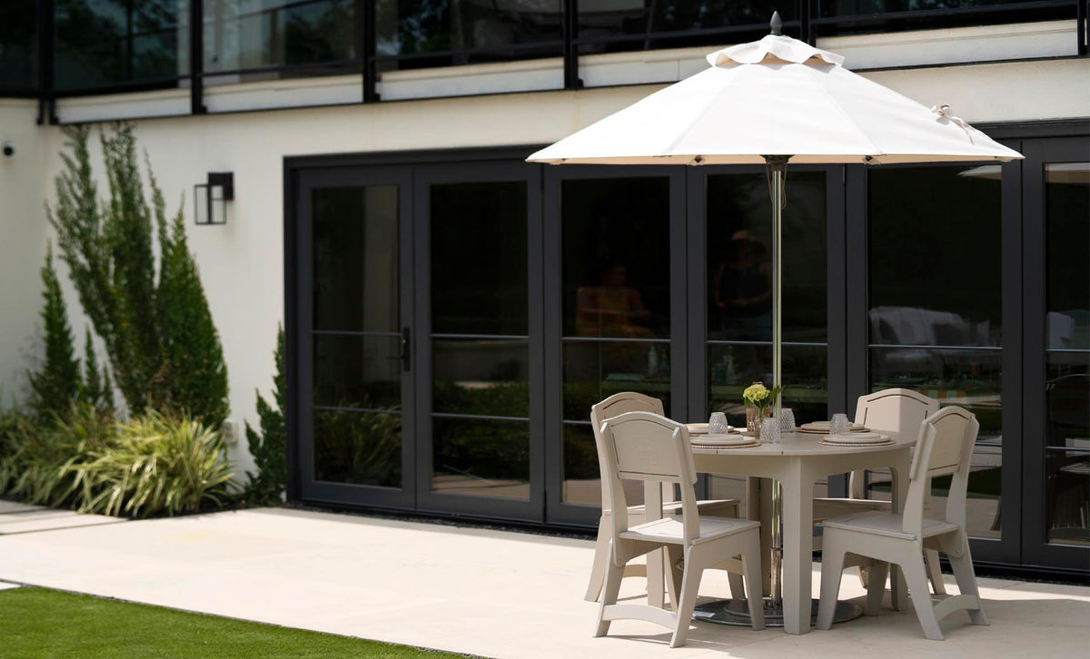 Mainstay Round Dining Table with chairs under an umbrella on a patio