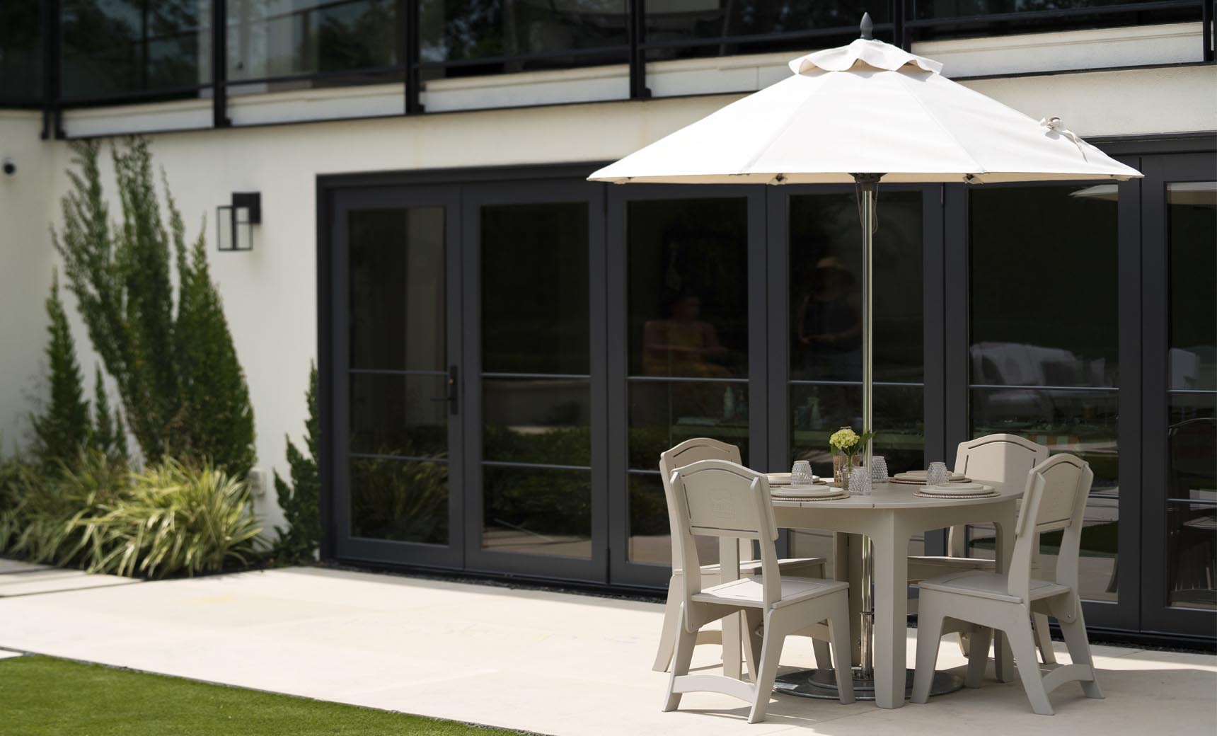 Mainstay Round Dining Table with chairs under an umbrella on a patio
