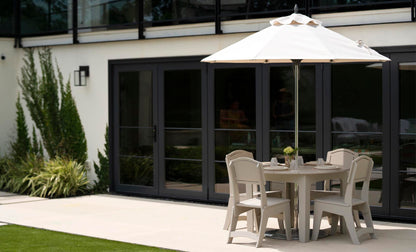 Mainstay Round Dining Table with chairs under an umbrella on a patio