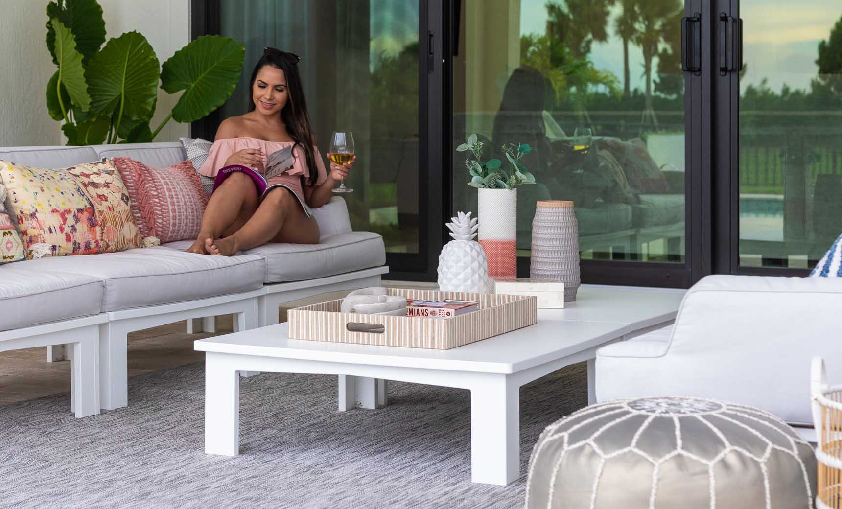 Woman relaxing on a patio sofa beside a white Mainstay Square Coffee Table