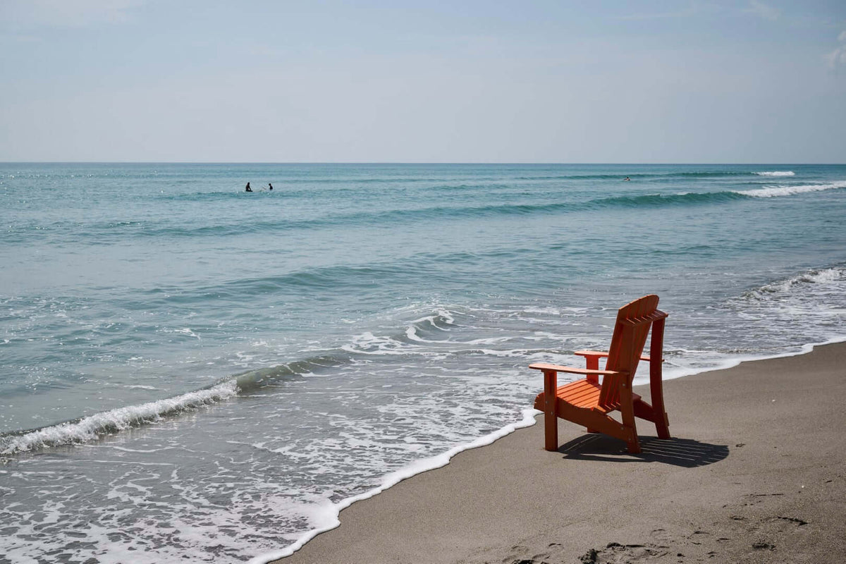 LuxCraft Royal Adirondack Chair in Tangerine styled for patio lounging — 20-year poly durability