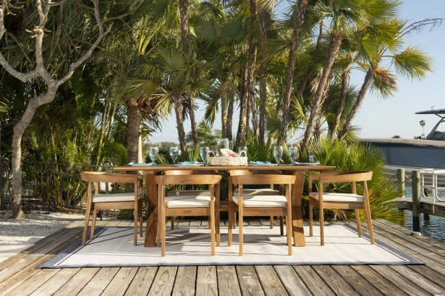 Panama Jack 7-piece outdoor rectangular dining table set made with Grade-A teak wood for a natural wood finish with cushions