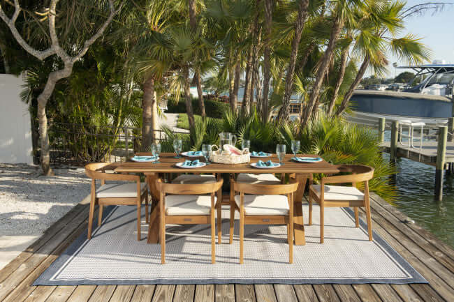 Panama Jack 7-piece outdoor rectangular dining table set made with Grade-A teak wood for a natural wood finish with cushions