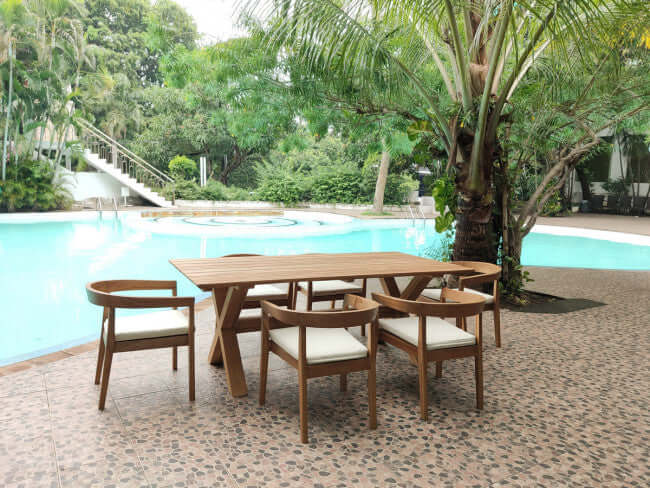 Panama Jack 7-piece outdoor rectangular dining table set made with Grade-A teak wood for a natural wood finish with cushions